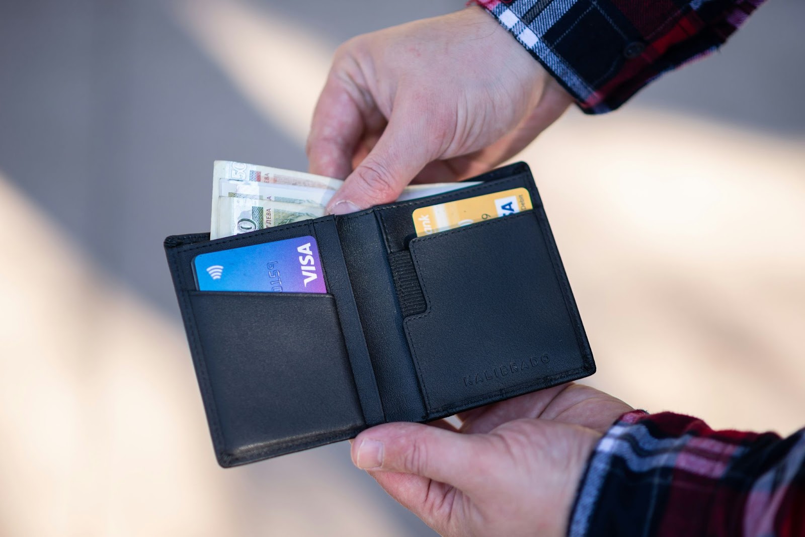 A peson holding a wallet and geeting money from it.