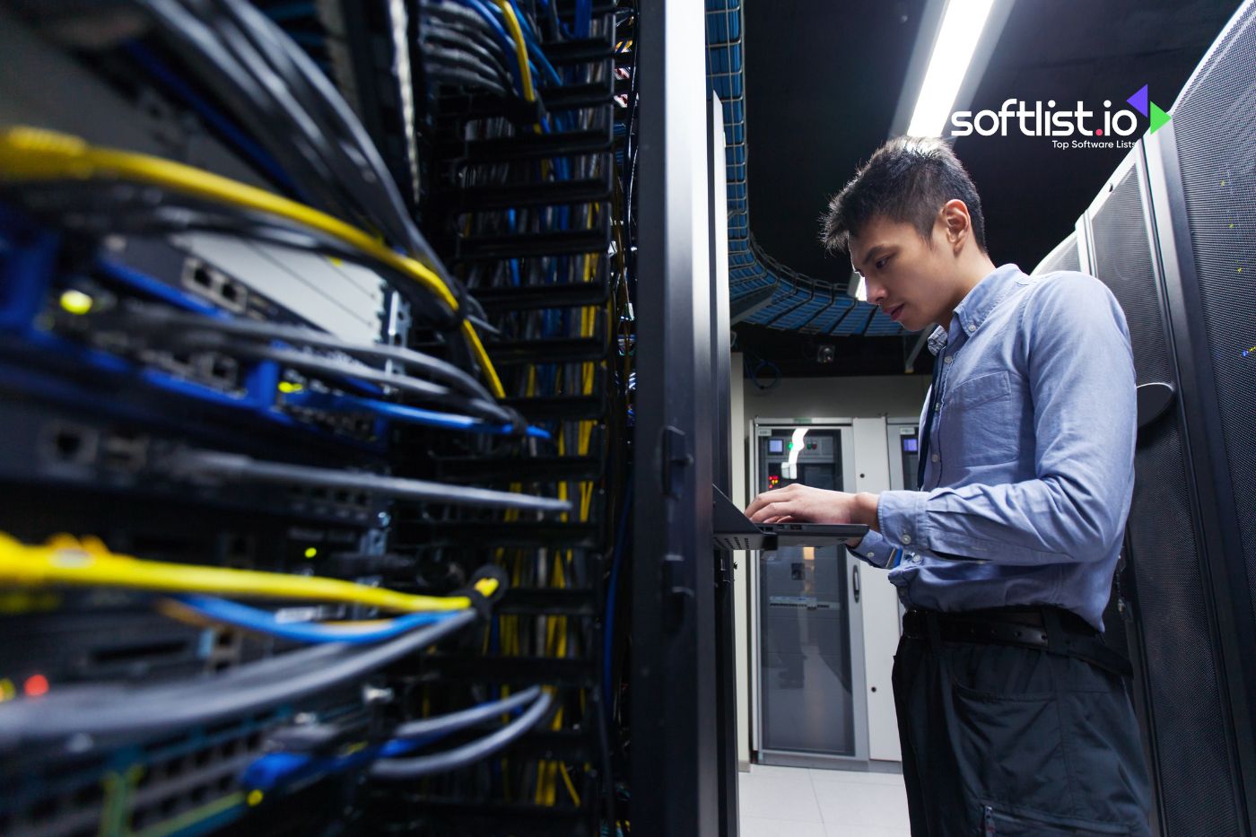 Technician working on a laptop, surrounded by server racks and cables