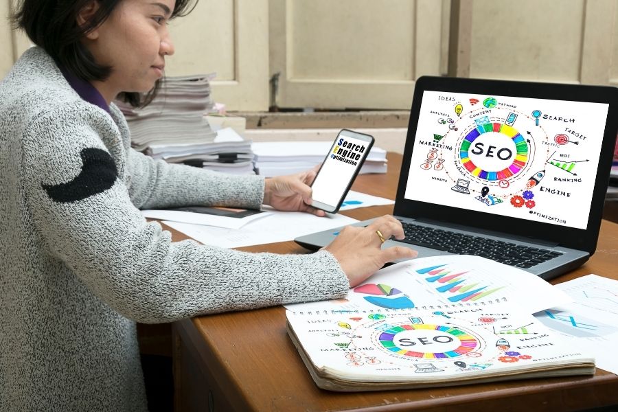 A woman working at a desk with a laptop and phone.