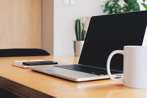 Free Macbook Pro on Tabletop Beside Mug Stock Photo