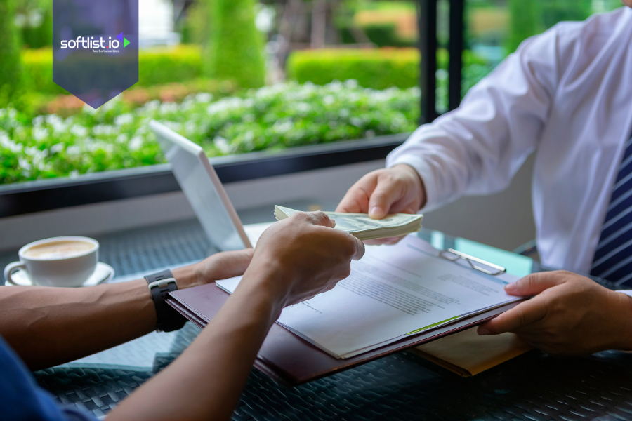 Two professionals exchange documents and cash during a business deal, representing a real-world mergers and acquisitions transaction facilitated in a modern setting.
