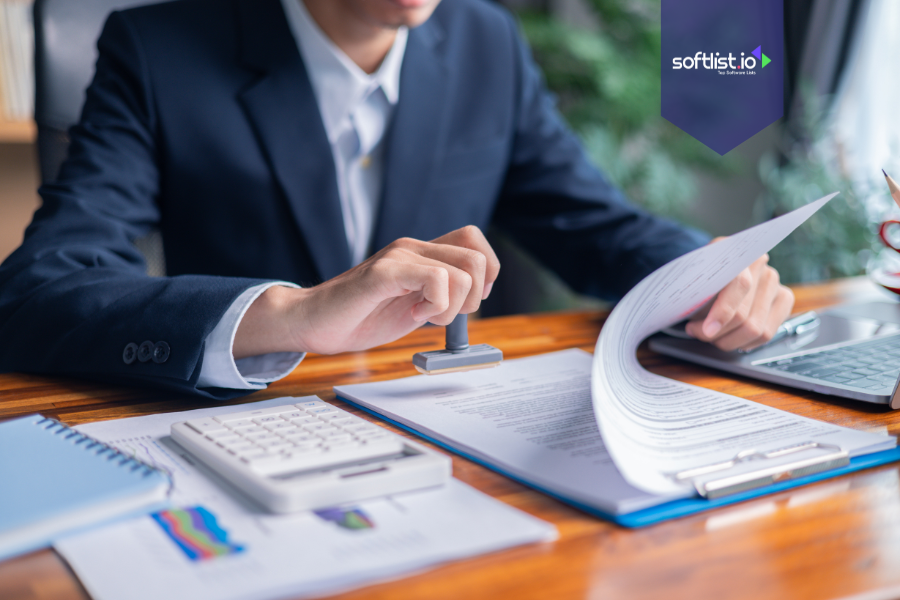 Business professional stamping documents with a calculator and charts on the desk, representing tax implications of selling an online business.