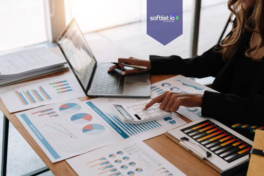 Person analyzing financial charts and using a calculator with a laptop, illustrating tax implications of selling an online business.