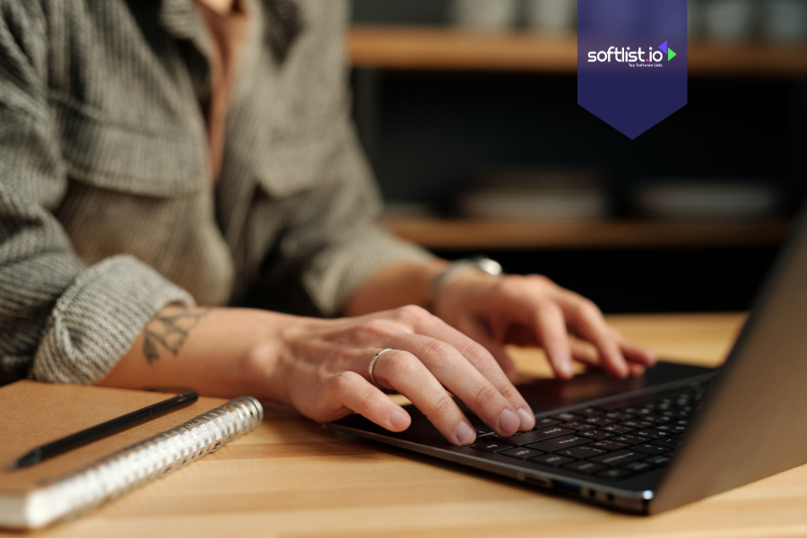 Close-up of hands typing on a laptop with a notebook nearby, symbolizing buying an online business as an individual.