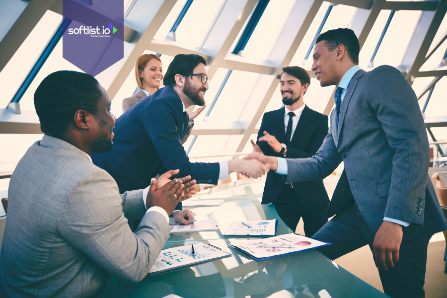 Business professionals shaking hands in a meeting, representing creative deal structures in business negotiations.