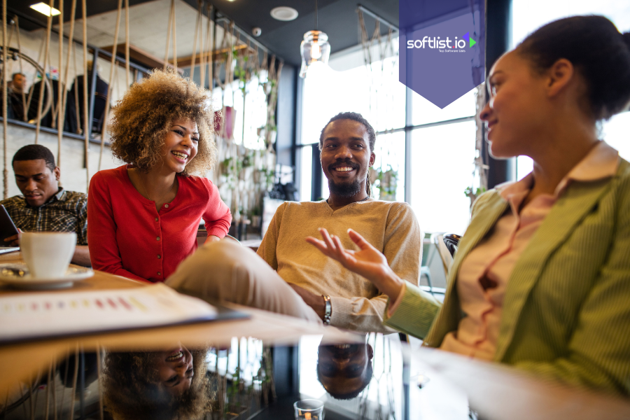 Group of professionals smiling and having a casual discussion at a table, representing community-driven business valuation through collaboration and engagement.